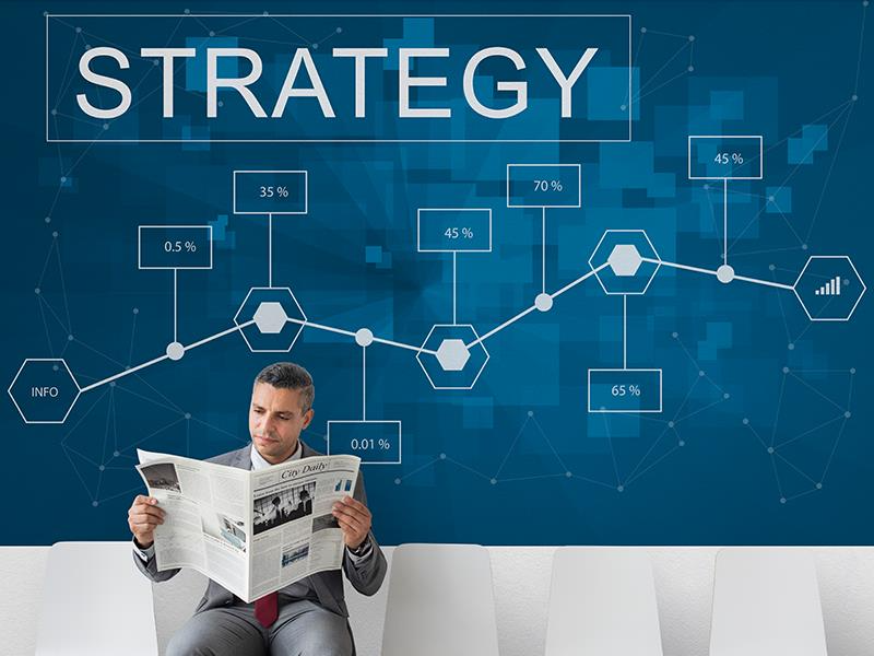 Man reading newspaper with strategy chart | Tech consultancy services Basecode